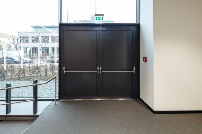 As portas de saída de emergência antipânico total de duas folhas também estão integradas no sistema técnico de gestão de edifícios. Foto: Jürgen Pollak para a GEZE GmbH